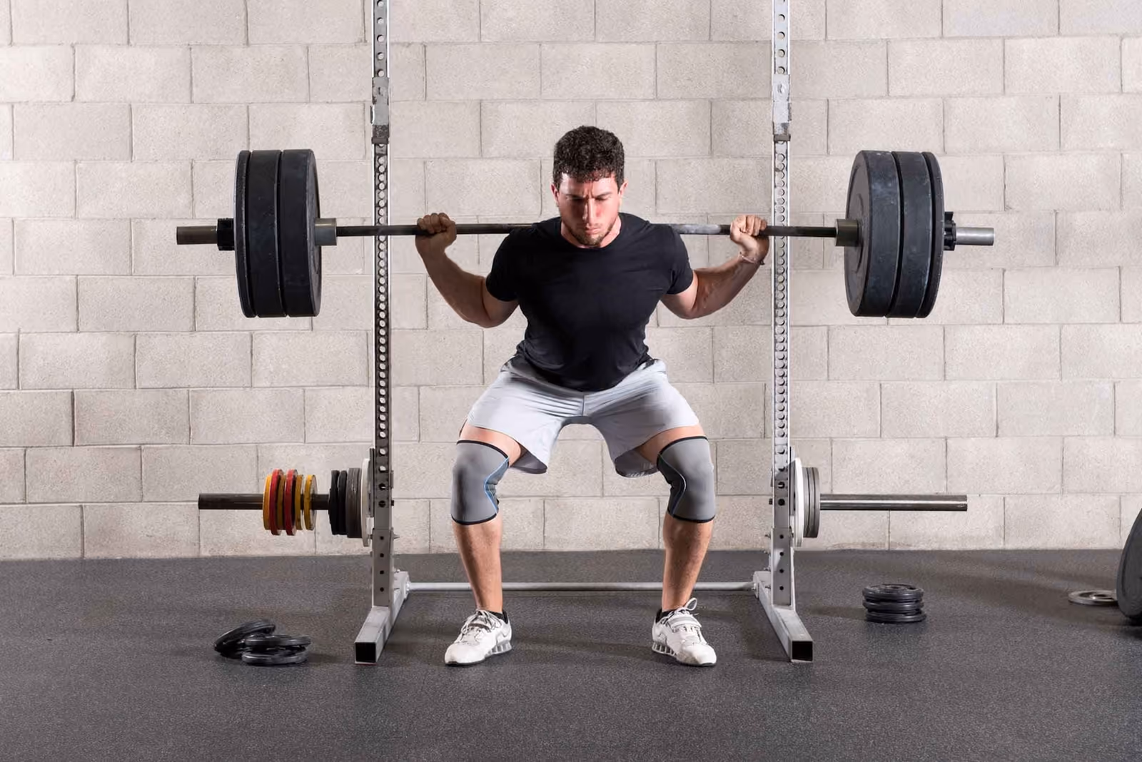 Athlète en squat barre sur le dos dans un rack de musculation